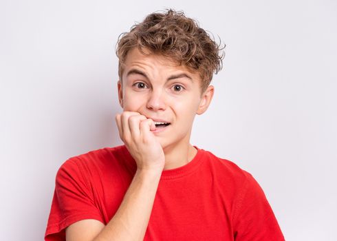 Portrait of surprised teen boy, on grey background. Funny child looking at camera in shock or amazement touching his head with hands