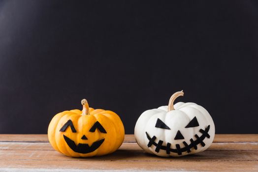 Funny Halloween day party concept ghost pumpkins head jack lantern scary smile on wooden table and black background, studio shot isolated, Holiday decoration