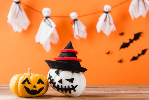 Funny Halloween day decoration party, Cute pumpkin ghost spooky jack o lantern face wear hat, black spider and bats on wooden table, studio shot isolated on an orange background, Happy holiday concept