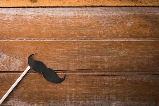 Black mustache paper on wooden background, Prostate cancer awareness month, Fathers day, minimal November moustache concept