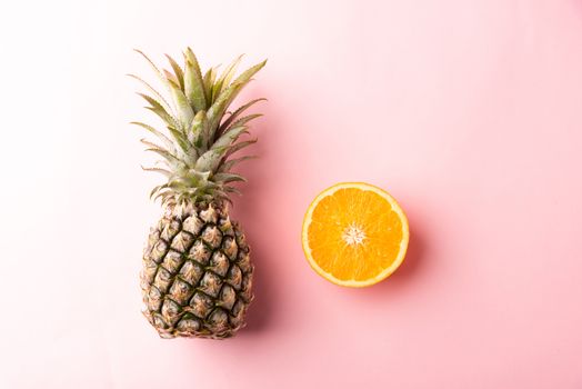 Close up above top view of ripe pineapple and orange fruit on pink pastel background, Summer Tropical, Healthy lifestyle diet food concept