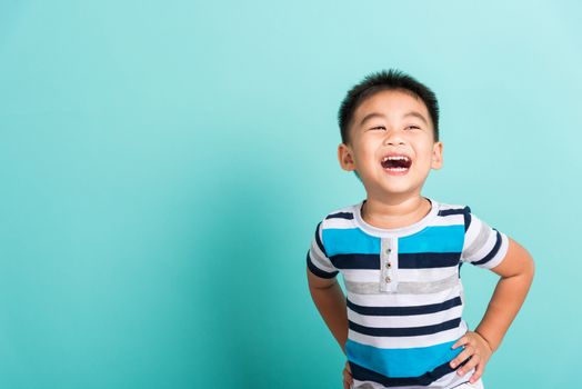 Asian portrait of cute little boy kid happy face he laughing smiles and looking to camera, studio shot isolated on blue background