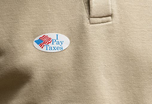I Pay Taxes sticker on mans T-shirt for anger about the lack of federal tax paid by president in the presidential election