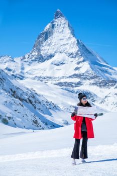Young female tourist looking map at Matterhorn in Switzerland with a magnificent panoramic view of the Swiss Skyline.