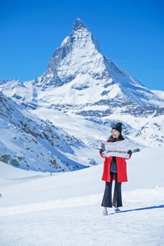 Young female tourist looking map at Matterhorn in Switzerland with a magnificent panoramic view of the Swiss Skyline.