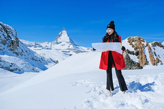 Young female tourist looking map at Matterhorn in Switzerland with a magnificent panoramic view of the Swiss Skyline.