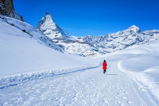 Young Woman Tourist walking in snow mountain Matterhorn peak, Zermatt, Switzerland.