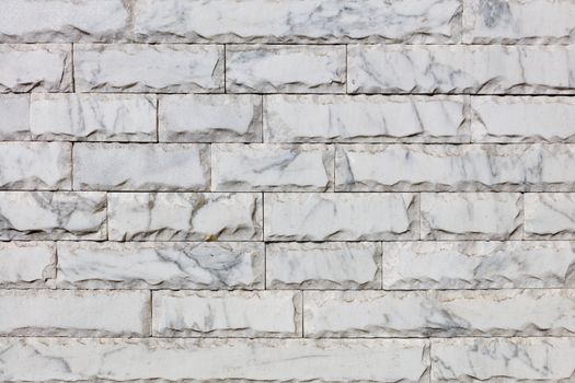 Wall background and texture of gray marble tiles with chips around the perimeter and brown veins on the surface, close-up.