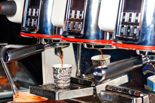 During the preparation of aromatic coffee, the coffee machine pours coffee into a cardboard cup.