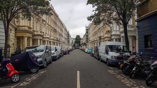 London, UK - July 8, 2020: View of a street in central London. Cars, vans, motorcycles parked on both sides of the street.