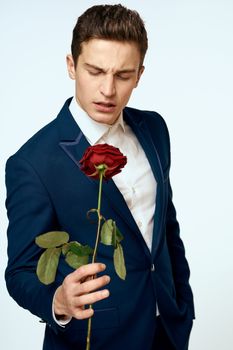 A man in a suit with a rose in his hands a gift date light background. High quality photo