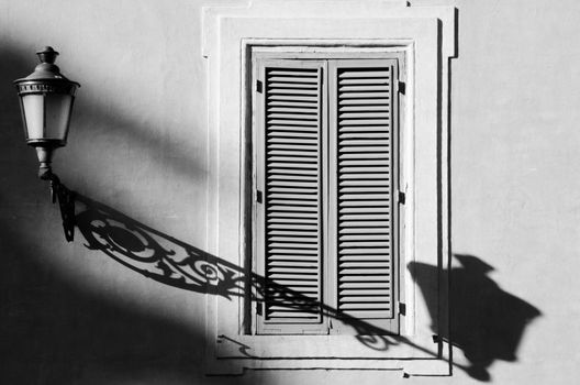Window and lamppost. Shadows in the early morning. Black and white photography
