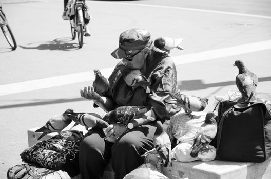 Rome, Italy. April 2019. Pigeons cover a homeless woman intent on feeding them