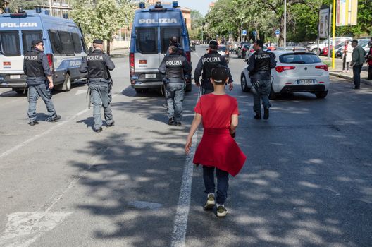 Rome, Italy. April 2019. A child dressed in red follows policemen during a political demonstration