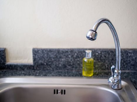 Faucet and bottle of dishwashing liquid On the sink.