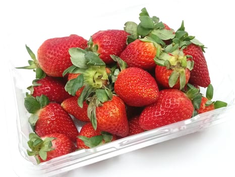 Fresh red strawberries with leaves placed in clear plastic container