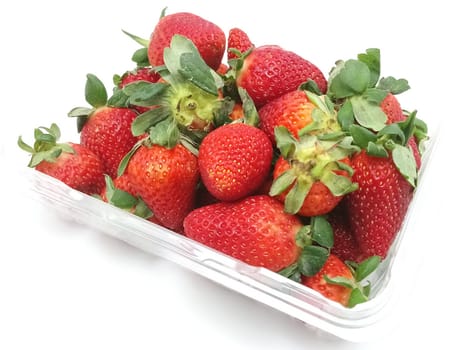 Fresh red strawberries with leaves placed in clear plastic container