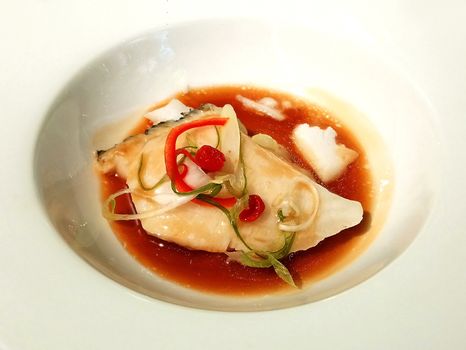 Steam fish with sauce on white bowl serve in hotel restaurant