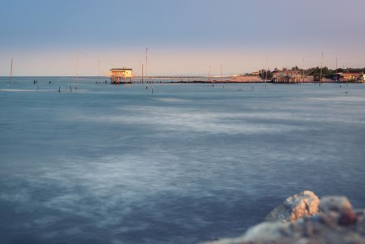 Fishing huts with typical italian fishing machine called trabucco ,at wonderful sunset .Lido di Dante, fiumi uniti Ravenna near Comacchio valley.