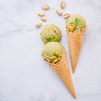 Pistachio ice cream in cones  with pistachio nuts setup on white stone background . Summer and Sweet menu concept.