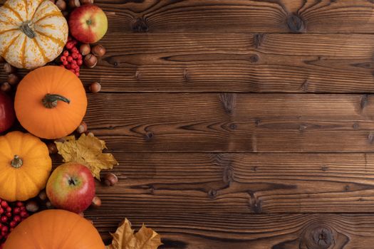 Autumn background with pumpkins, apples and nuts. Dark rustic wooden background with copy space for text