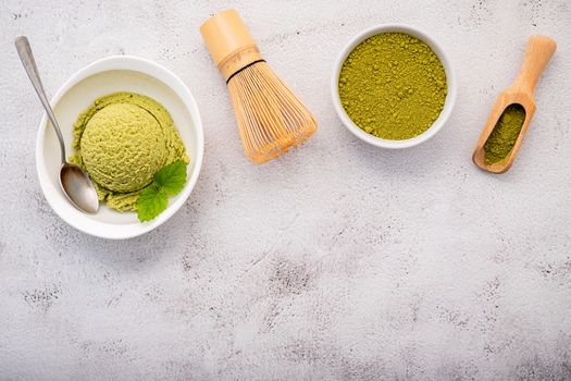 Matcha green tea ice cream with matcha whisk brush  setup on white stone background . Summer and Sweet menu concept.