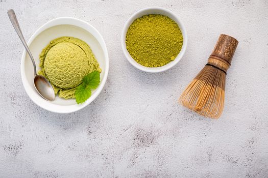 Matcha green tea ice cream with matcha whisk brush  setup on white stone background . Summer and Sweet menu concept.