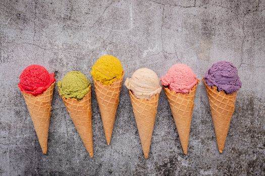 Various of ice cream flavor in cones blueberry ,green tea ,pistachio ,almond ,orange and cherry setup on dark stone background . Summer and Sweet menu concept.