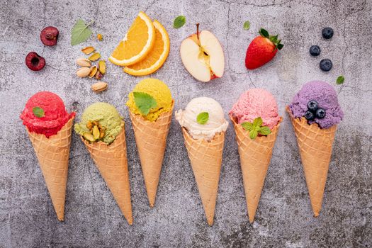 Various of ice cream flavor in cones blueberry ,green tea ,pistachio ,almond ,orange and cherry setup on dark stone background . Summer and Sweet menu concept.