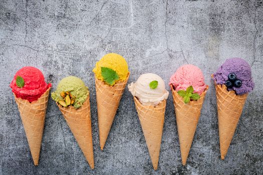 Various of ice cream flavor in cones blueberry ,green tea ,pistachio ,almond ,orange and cherry setup on dark stone background . Summer and Sweet menu concept.