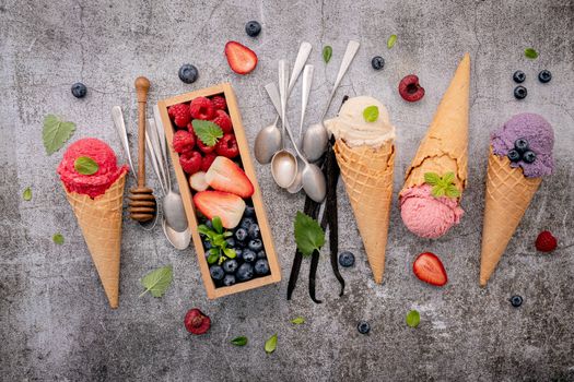 Various of ice cream flavor in cones with berries in wooden box setup on concrete background . Summer and Sweet menu concept.