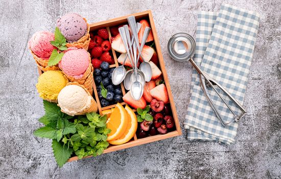 Various of ice cream flavor in cones with berries in wooden box setup on concrete background . Summer and Sweet menu concept.