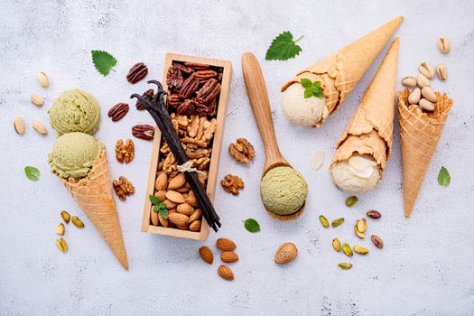 Pistachio and vanila ice cream in cones  with mixed nut setup on white stone background . Summer and Sweet menu concept.