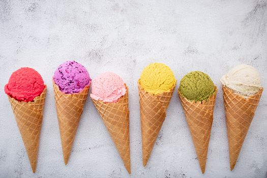 Various of ice cream flavor in cones blueberry ,pistachio ,almond ,orange and cherry setup on white stone background . Summer and Sweet menu concept.