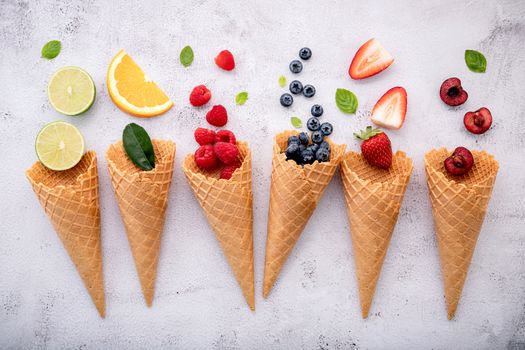 Various of fruits  in cones blueberry ,strawberry ,raspberries and strawberry setup on white stone background . Summer and Sweet menu concept.