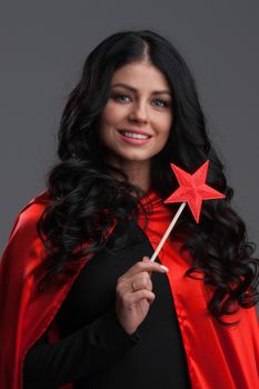 Woman with star shaped magic wand on gray background, halloween costume