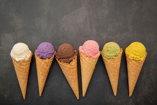 Various of ice cream flavor in cones blueberry ,pistachio ,almond ,orange and chocolate setup on dark stone background . Summer and Sweet menu concept.