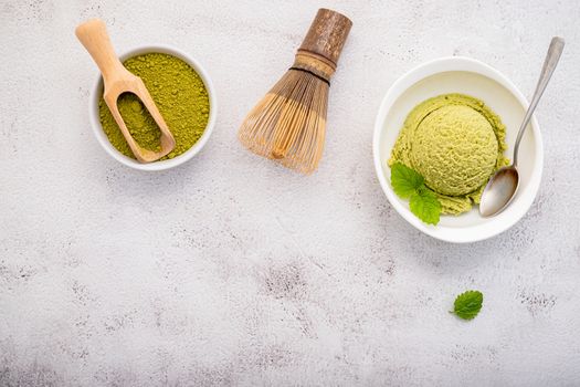 Matcha green tea ice cream with matcha whisk brush  setup on white stone background . Summer and Sweet menu concept.