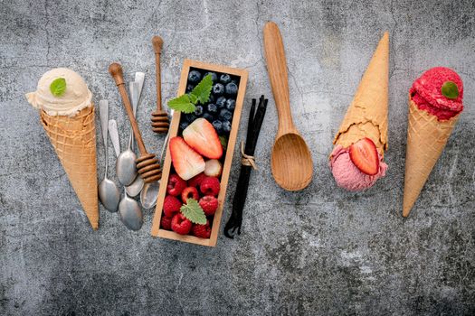 Various of ice cream flavor in cones with berries in wooden box setup on concrete background . Summer and Sweet menu concept.