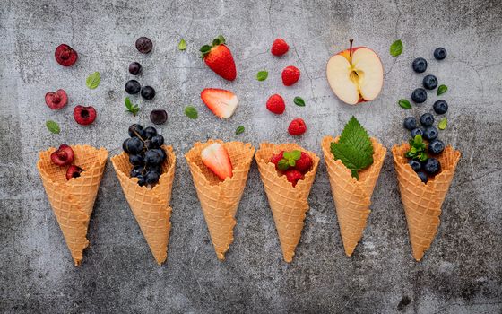 Various of fruits  in cones blueberry ,strawberry ,raspberries and strawberry setup on white stone background . Summer and Sweet menu concept.