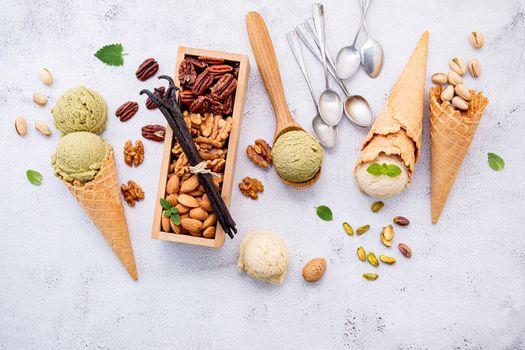 Pistachio and vanila ice cream in cones  with mixed nut setup on white stone background . Summer and Sweet menu concept.