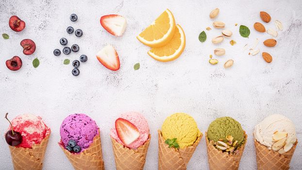 Various of ice cream flavor in cones blueberry ,pistachio ,almond ,orange and cherry setup on white stone background . Summer and Sweet menu concept.