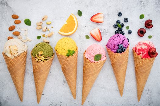 Various of ice cream flavor in cones blueberry ,pistachio ,almond ,orange and cherry setup on white stone background . Summer and Sweet menu concept.