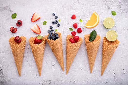 Various of fruits  in cones blueberry ,strawberry ,raspberries and strawberry setup on white stone background . Summer and Sweet menu concept.