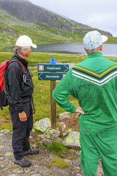 Hikers on the Hydnefossen waterfall make a decision on Veslehødn Veslehorn mountain in Hemsedal, Norway.