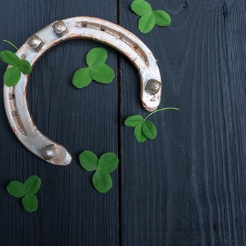clover leaves and golden horseshoe on vintage wooden boards, selective focus. Good luck symbol, St. Patrick's Day and New Year concept.
