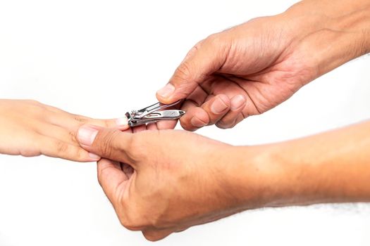 Closeup father's hand is using stainless steel nail clippers to cut the son's fingernail on white background.