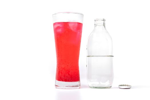 Glass of red nectar mixed with soda and soda bottles that open the lid on white background.