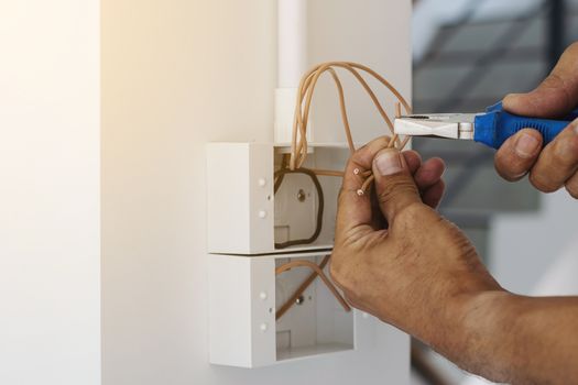 Electricians are using a pliers wrench to install the power plug on the wall.