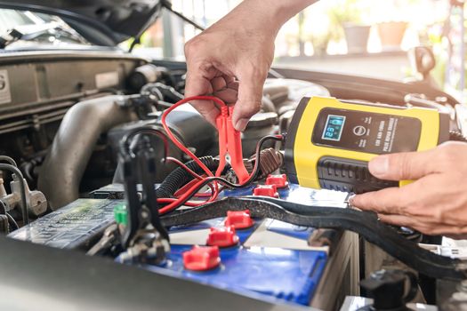 The car mechanic is using a voltage measuring instrument and charging the battery, the car's battery power.